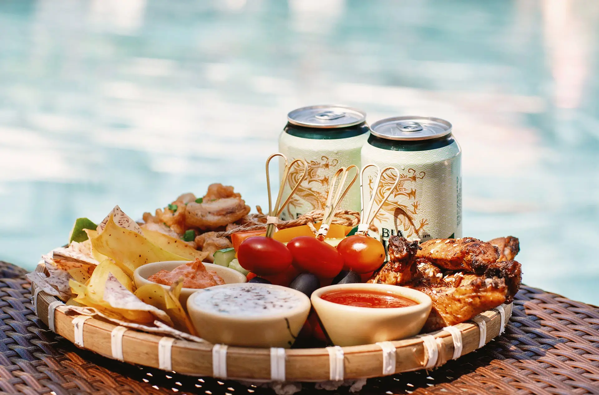 Snack and Sip. Thực đơn tán gẫu: hai ly bia ướp lạnh, combo ba món nhắm đặc sản đậm đà vị biển: gà nướng mật ong, mực chiên giòn, khoai lang chiên, Sun Terrace. Golden sunlight glimmers softly across the pool as summer slowly settles in. The Chat-and-Chill Set